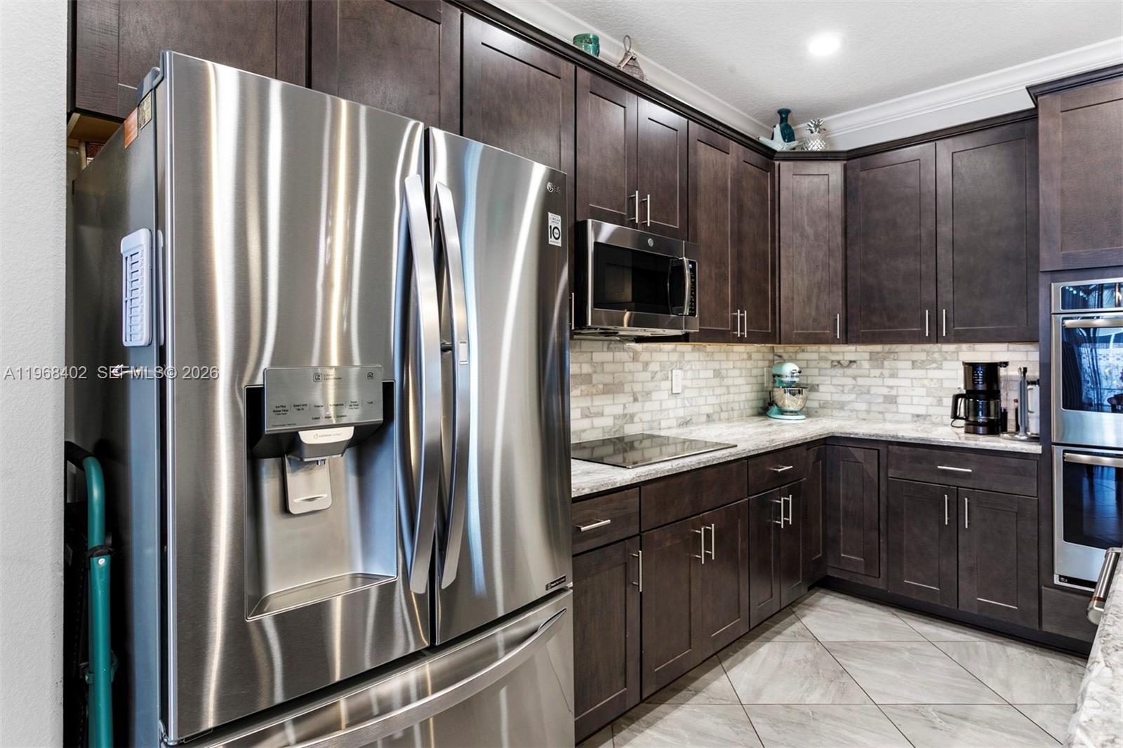 1773 Southwest Palermo Road Port St. Lucie, FL 34987 - Photo 12 of 50 Chef's quality kitchen with Quartz top island, marble backsplash with undermount lighting, wood cabinetry, SS appliances, double oven, and pantry.