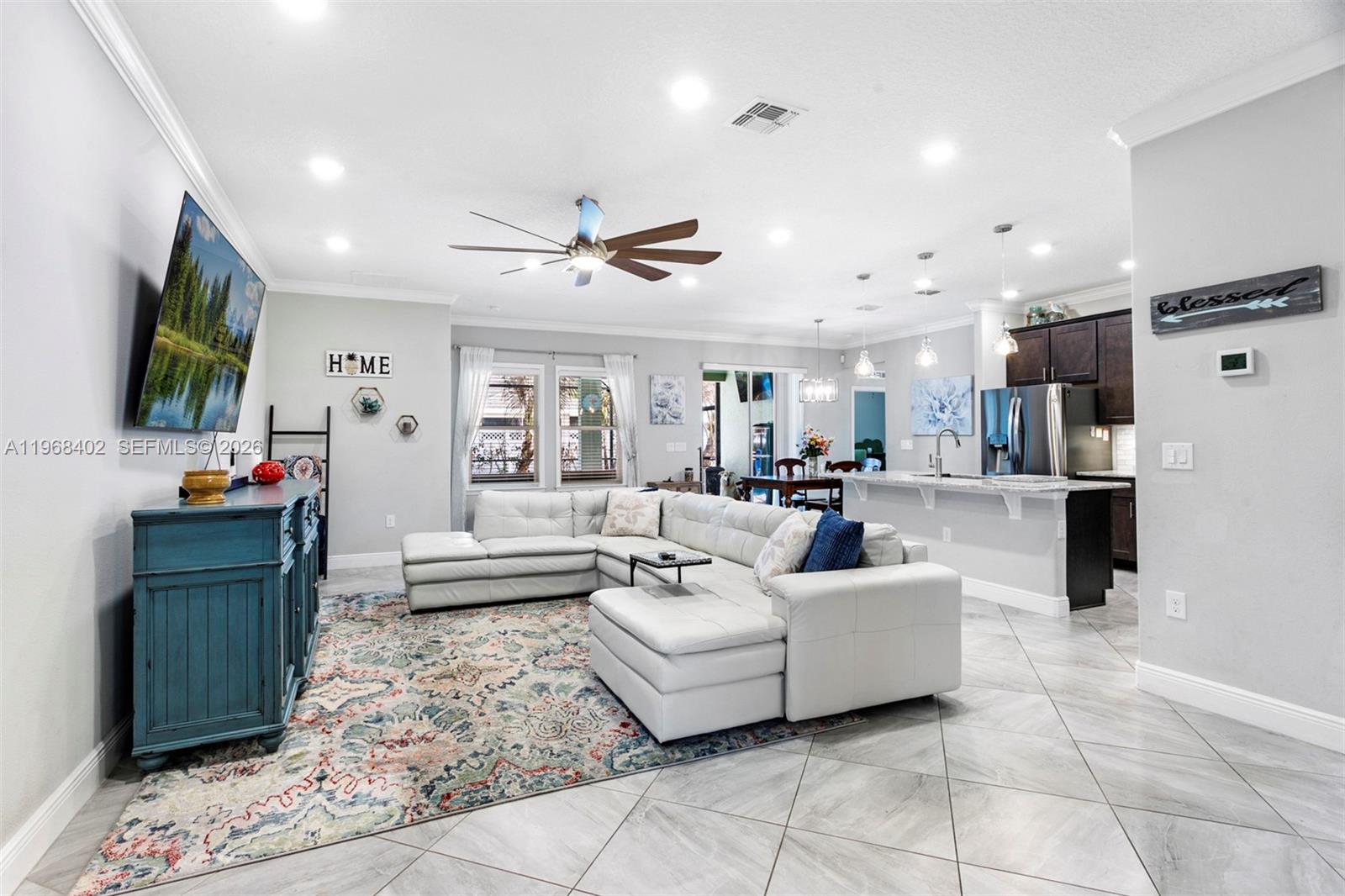 1773 Southwest Palermo Road Port St. Lucie, FL 34987 - Photo 8 of 50 Living room/kichen/dining room. Wide open floorplan featuring large neutral tile flooring, high hat lighting, newer fan/light, views to pool/patio!