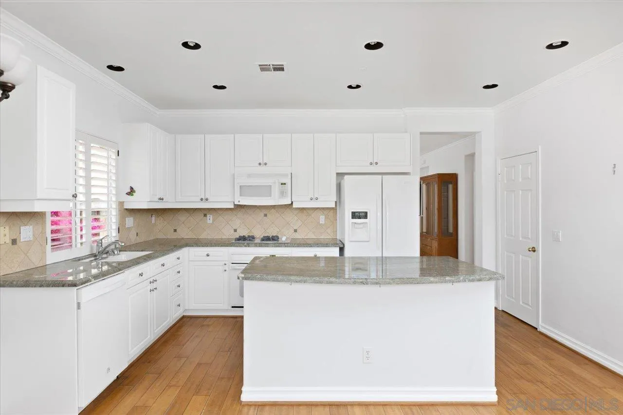 2314 Fallbrook Place Escondido, CA 92027 - Photo 13 of 30 a large kitchen with granite countertop a sink dishwasher a refrigerator and white cabinets with wooden floor