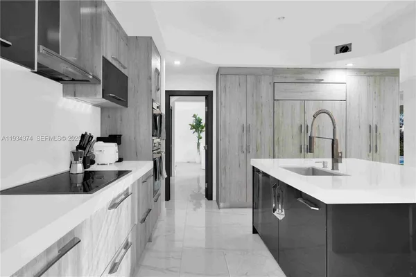 a large kitchen with a large counter top a sink stainless steel appliances and cabinets