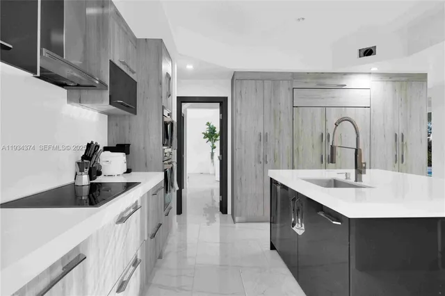 a large kitchen with a large counter top a sink stainless steel appliances and cabinets