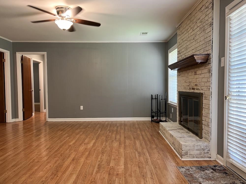7935 Memphis Arlington Road Bartlett, TN 38133 - Photo 7 of 20 Living area featuring a brick fireplace with a wood mantle, wood-finish flooring, and paneling accent wall