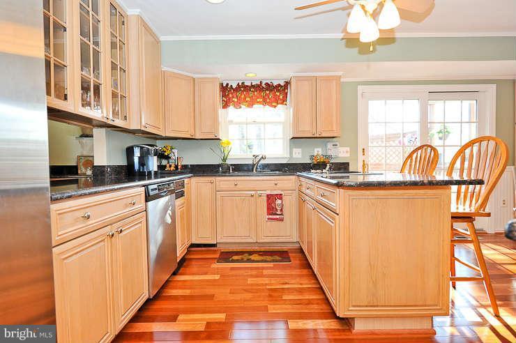 8901 Spur Road Springfield, VA 22153 - Photo 11 of 30 a kitchen with stainless steel appliances granite countertop a stove a sink dishwasher and white cabinets with wooden floor