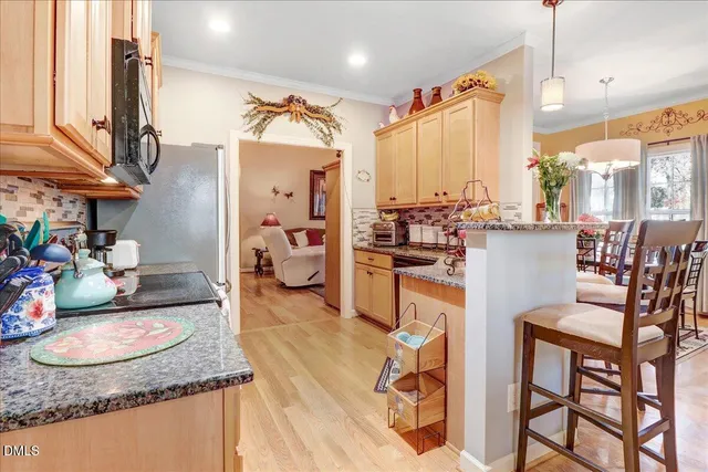 a kitchen with stainless steel appliances granite countertop table chairs and a wooden floor