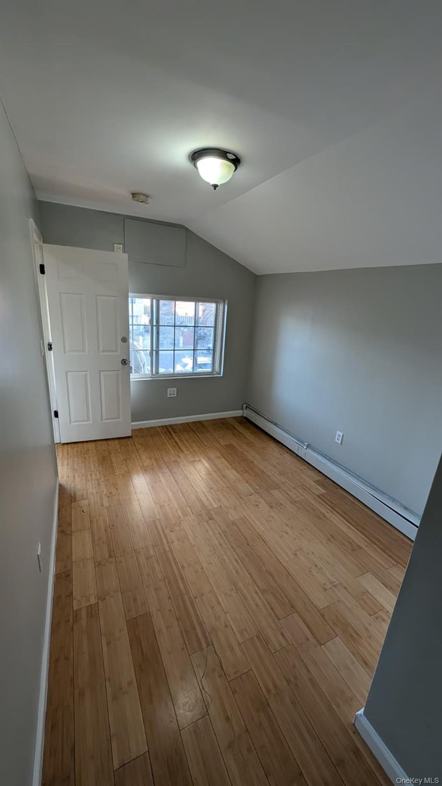 134-15 228th Street, Unit 2 Queens, NY 11413 - Photo 12 of 16 an empty room with wooden floor and windows