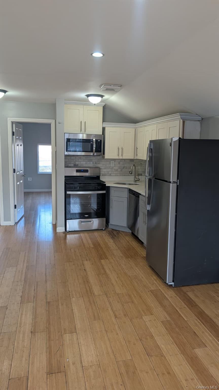 134-15 228th Street, Unit 2 Queens, NY 11413 - Photo 2 of 16 a kitchen with stainless steel appliances a refrigerator and wooden floor
