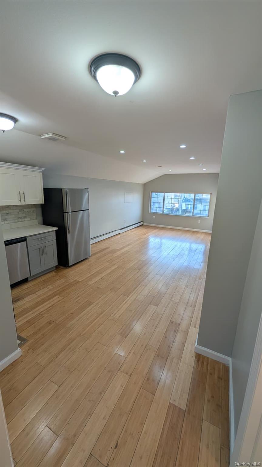 134-15 228th Street, Unit 2 Queens, NY 11413 - Photo 10 of 16 an empty room with wooden floor and windows