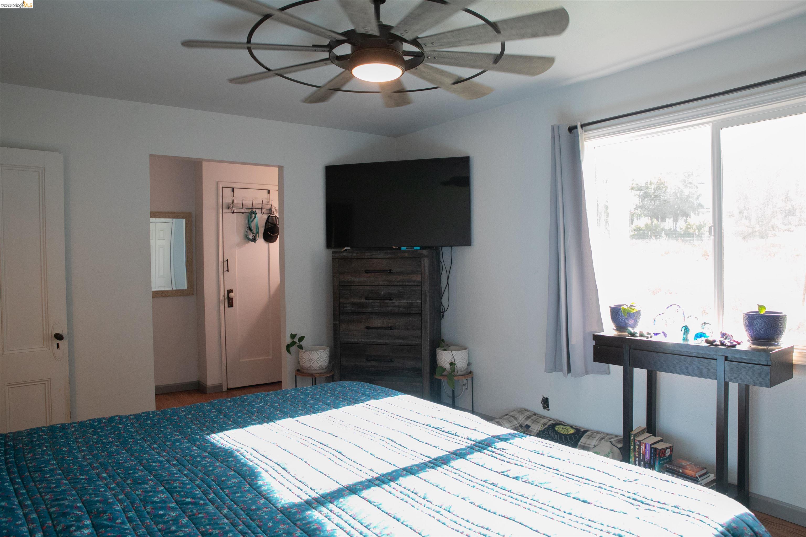 20982 Shaws Flat Road Sonora, CA 95370 - Photo 22 of 26 Bedroom featuring a large window with natural light, a ceiling fan with integrated lighting, wood-finish flooring, and white interior doors