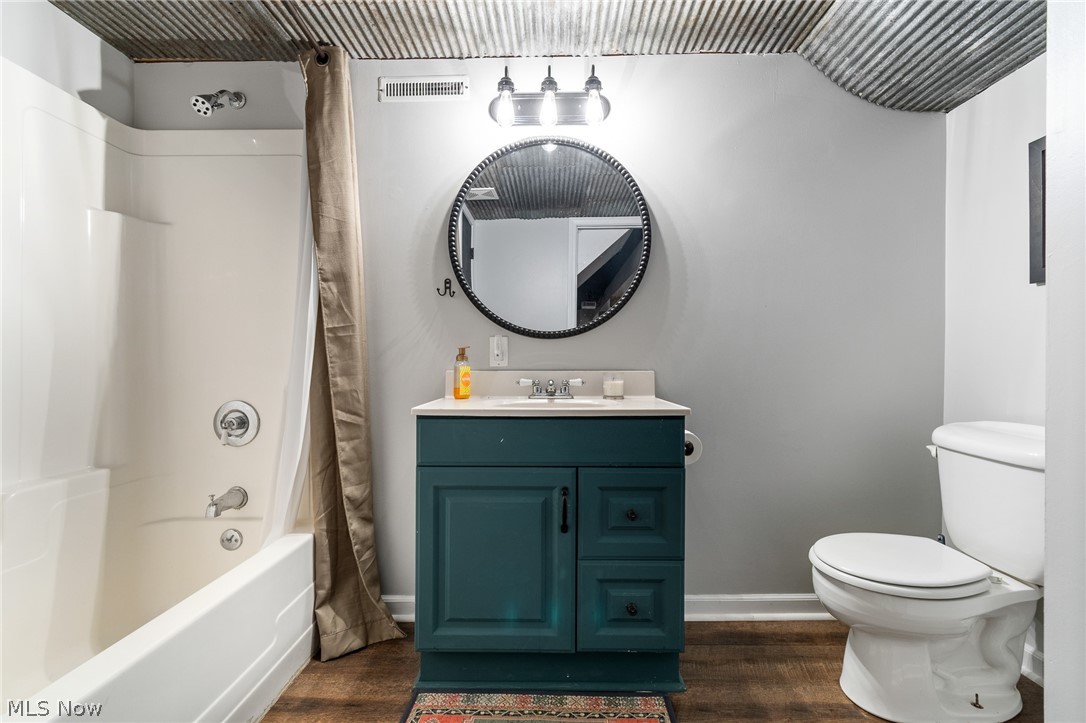 2119 Johns Road Clinton, OH 44216 - Photo 43 of 48 Vanity with a white countertop and teal-painted cabinetry, white toilet, and a white bathtub with an integrated shower