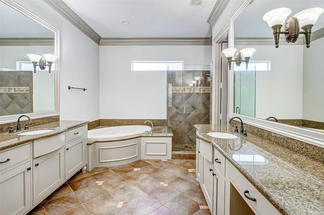 a bathroom with a granite countertop double vanity sink and mirror with bathtub