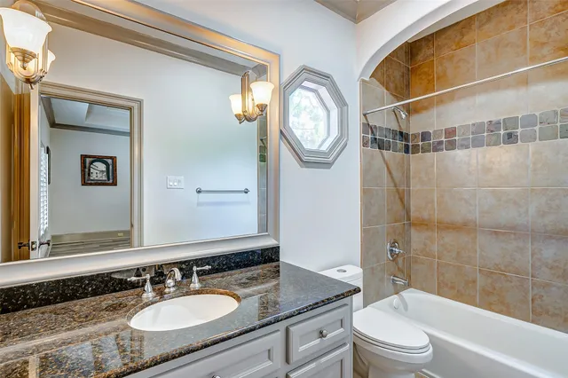 a bathroom with a granite countertop sink toilet a mirror and shower