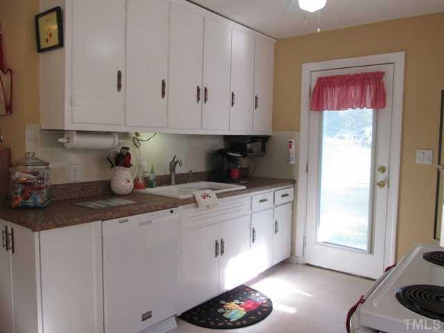 5507 Meadowbrook Road Raleigh, NC 27603 - Photo 18 of 25 Another view of your kitchen with updated counter tops, dishwasher, microwave, pantry, and the side door leads to fenced in area of side yard, lots of natural light so kitchen cheery and bright!