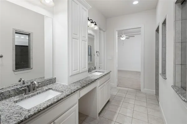 a bathroom with a granite countertop double vanity sink and a mirror