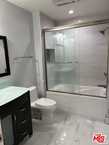 a bathroom with a bathtub shower sink vanity and toilet