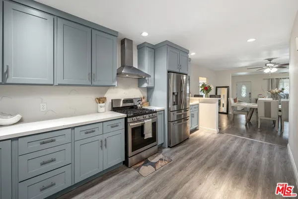 a kitchen with stainless steel appliances granite countertop a stove a sink dishwasher and a refrigerator with wooden floor