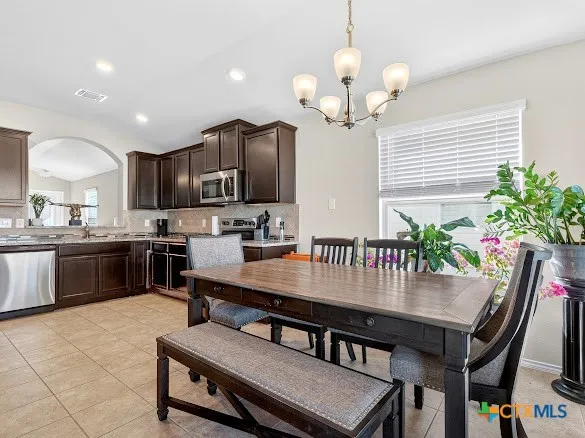 a kitchen with granite countertop a table chairs stainless steel appliances and cabinets