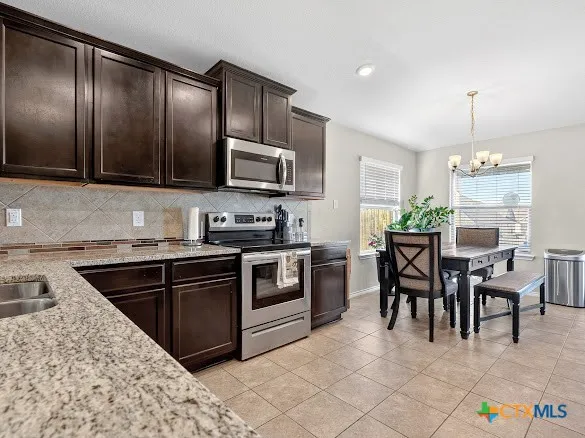 a kitchen with granite countertop cabinets stainless steel appliances and a dining table