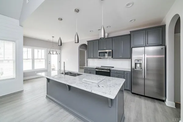 a kitchen with kitchen island stainless steel appliances a sink a stove and refrigerator