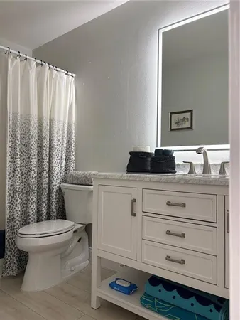 a bathroom with a granite countertop sink toilet and mirror
