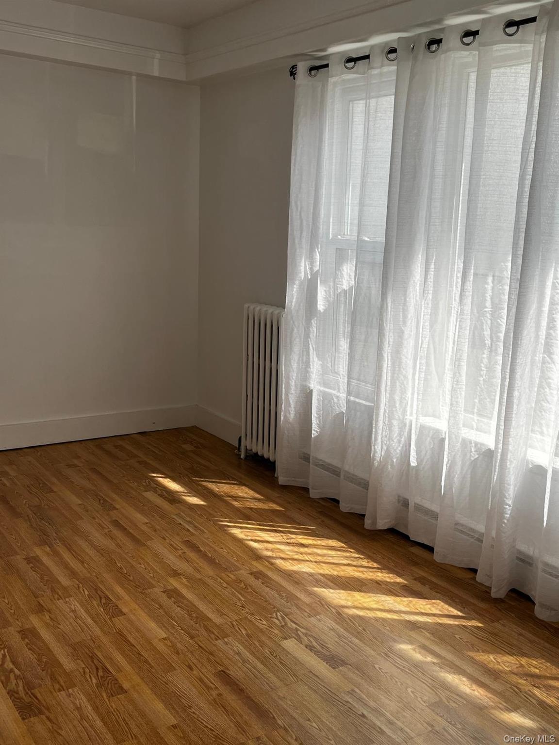 440 Mile Square Road Yonkers, NY 10701 - Photo 18 of 29 Room featuring wood-finish flooring, white baseboards, and a large window with sheers