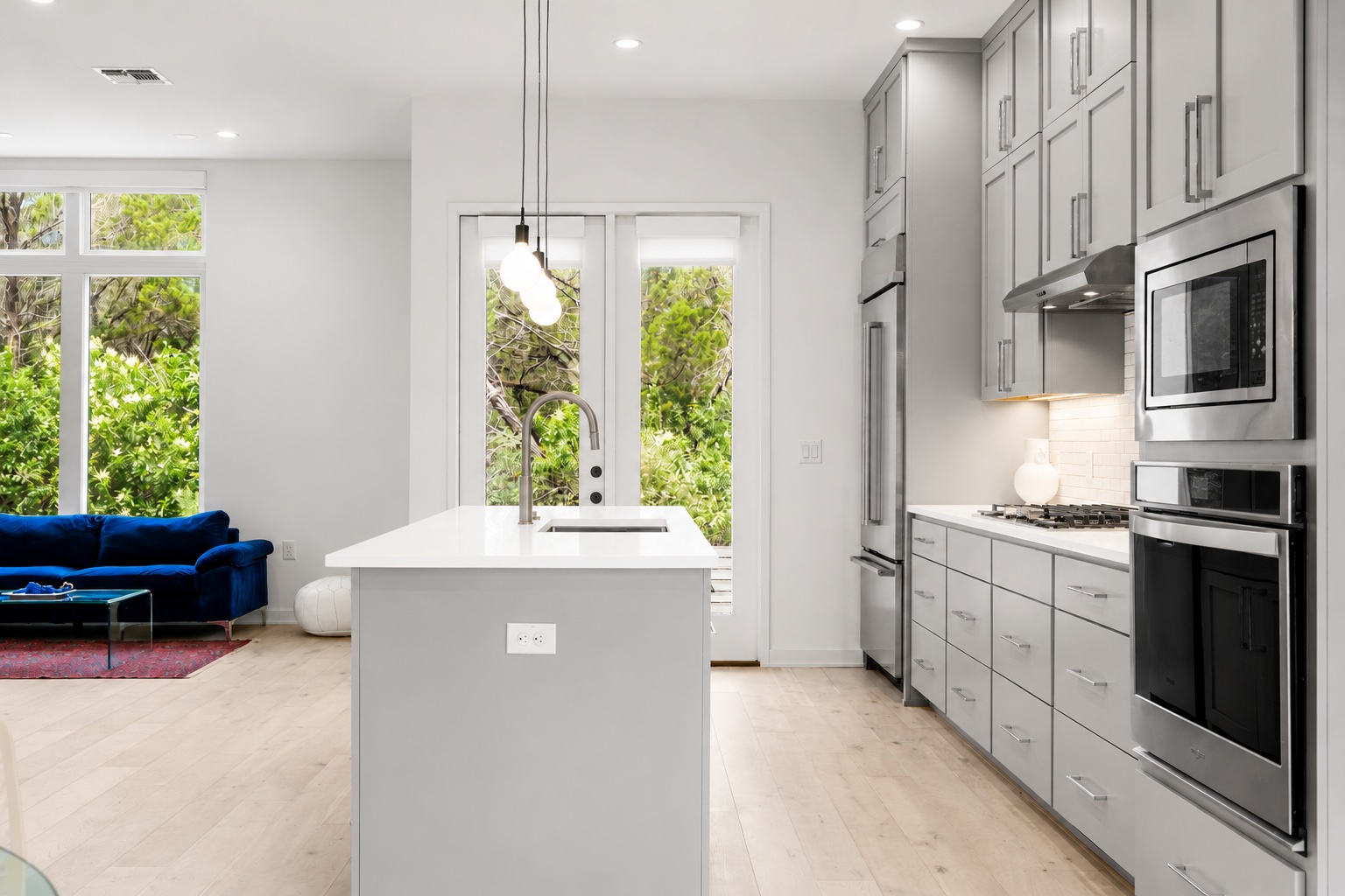 2520 Sutherland Street Austin, TX 78746 - Photo 7 of 26 A sleek island kitchen flows into a sun-drenched living area with abundant natural light and outdoor access.