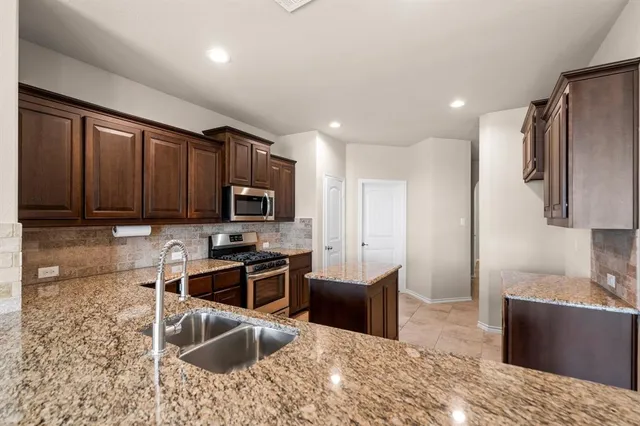 a kitchen with stainless steel appliances granite countertop a sink stove and refrigerator