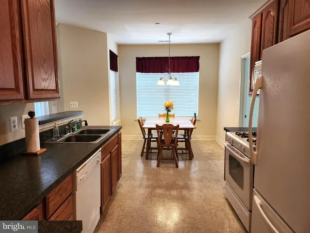 a kitchen with stainless steel appliances granite countertop a stove top oven a sink a dining table and chairs with wooden floor