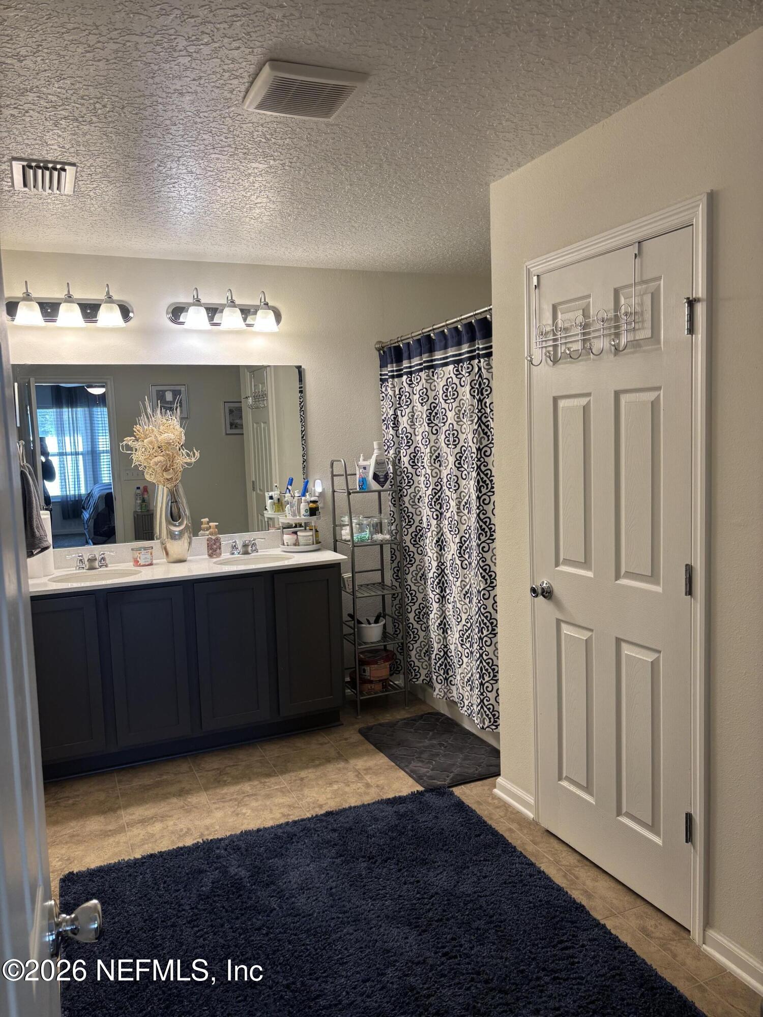8280 Fouraker Forest Road Jacksonville, FL 32221 - Photo 14 of 25 a bathroom with a sink a mirror and a shower
