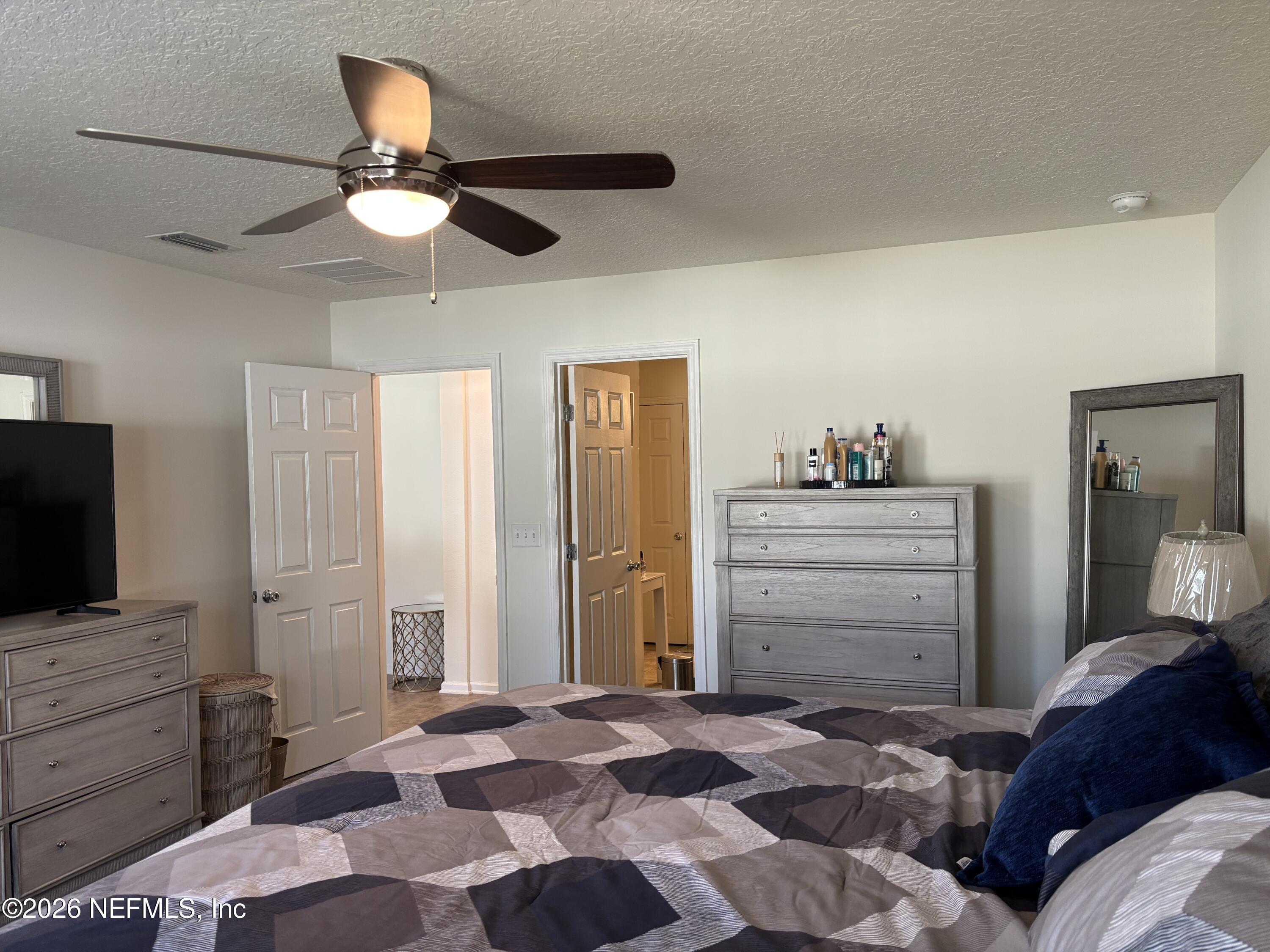 8280 Fouraker Forest Road Jacksonville, FL 32221 - Photo 18 of 25 a bedroom with a bed and a flat screen tv