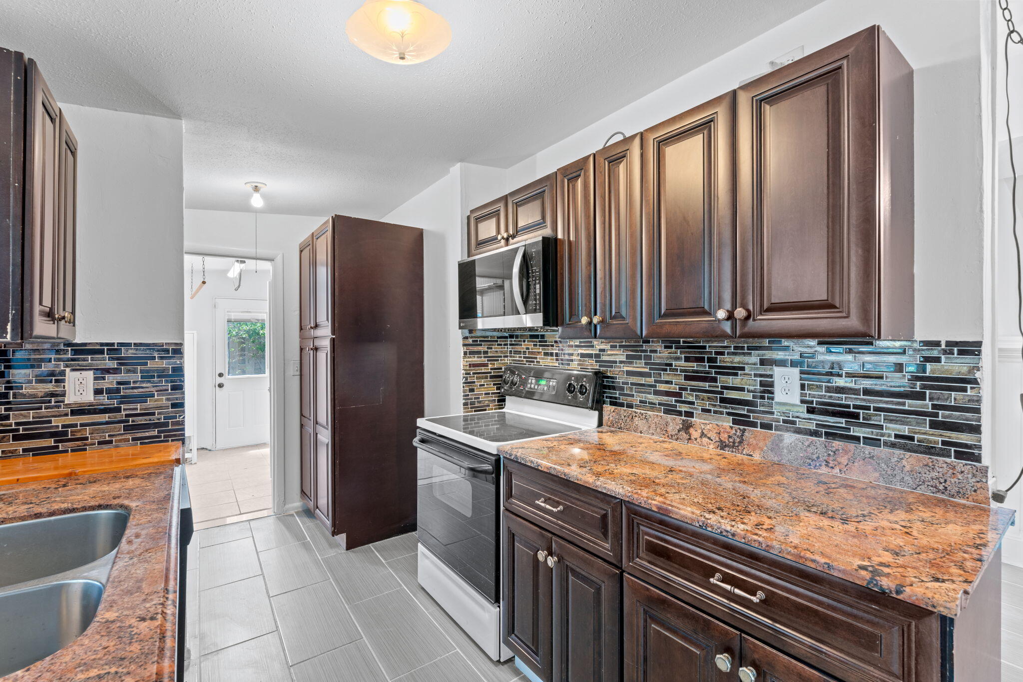3852 Catalina Road Palm Beach Gardens, FL 33410 - Photo 20 of 48 a kitchen with stainless steel appliances granite countertop a refrigerator a stove and a sink with wooden cabinets