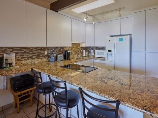 2075 South Kihei Road, Unit 114 Kihei, HI 96753 - Photo 7 of 14 a kitchen with stainless steel appliances granite countertop a table chairs sink and cabinets