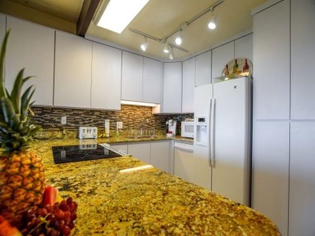 2075 South Kihei Road, Unit 114 Kihei, HI 96753 - Photo 9 of 14 a kitchen with granite countertop a refrigerator and a sink