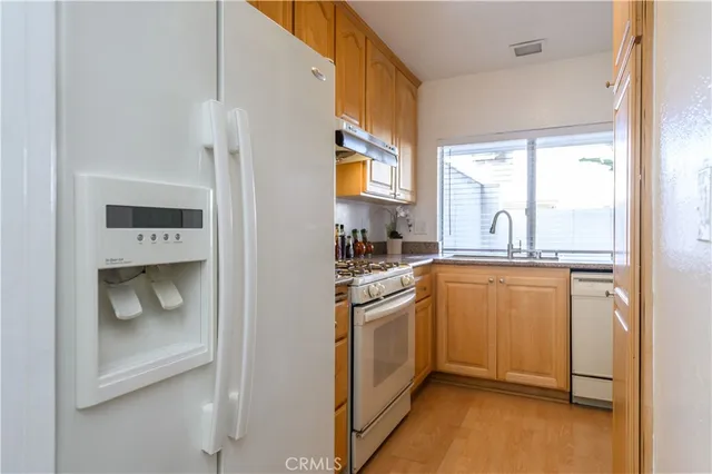 a kitchen with stainless steel appliances granite countertop a refrigerator a sink a stove and a window