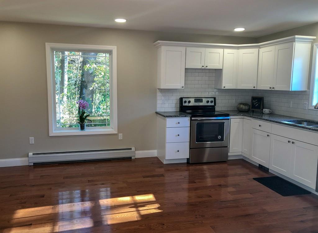 499 Jacksonville Road Colrain, MA 01340 - Photo 7 of 30 a kitchen with stainless steel appliances granite countertop wooden floors a stove a microwave and a window