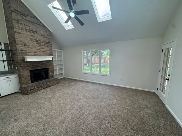 an empty room with windows and fireplace