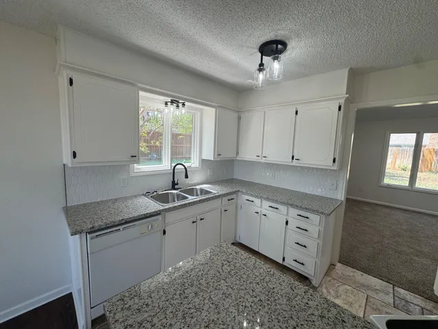 a kitchen with granite countertop a sink cabinets window and stainless steel appliances