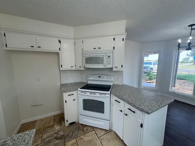 a kitchen with granite countertop a stove a sink and a microwave