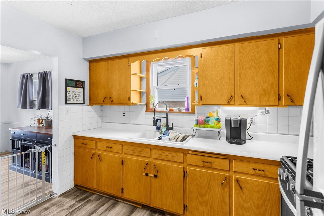 464 Elm Street Struthers, OH 44471 - Photo 12 of 22 Kitchen with light countertops, wood finish cabinets, stainless steel range with gas stovetop, light wood-style flooring, and refrigerator