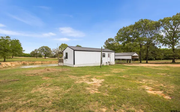 a front view of a house with a garden and lake view