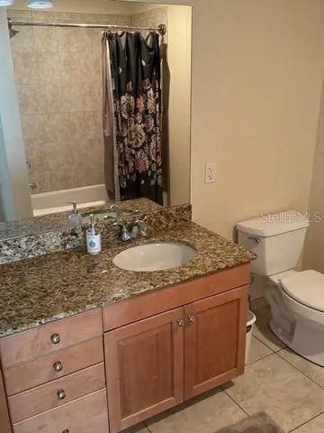a bathroom with a granite countertop sink a toilet and shower