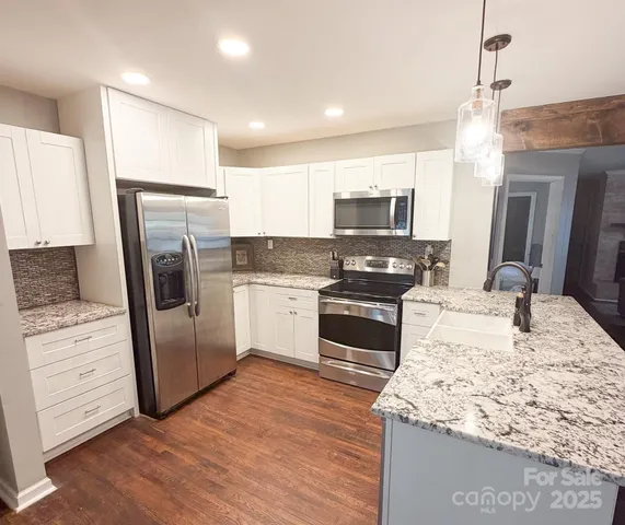 a kitchen with stainless steel appliances kitchen island granite countertop a refrigerator a stove a sink and a microwave