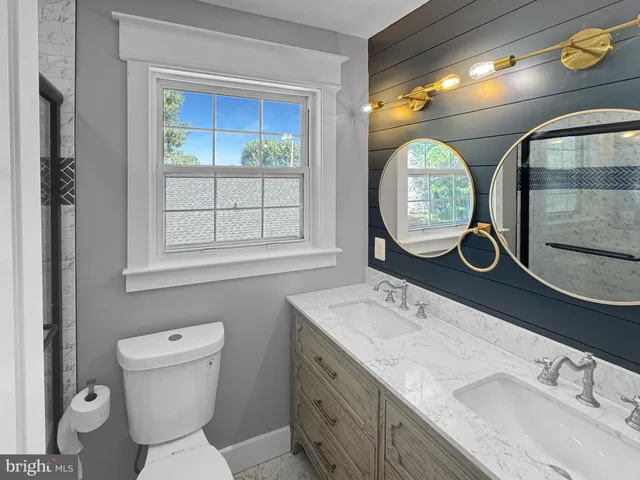 a bathroom with a granite countertop toilet a sink and a mirror