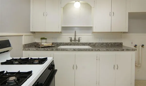 a kitchen with granite countertop white cabinets and white appliances