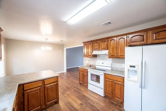 a kitchen with stainless steel appliances granite countertop a stove a sink dishwasher and a refrigerator with wooden floor
