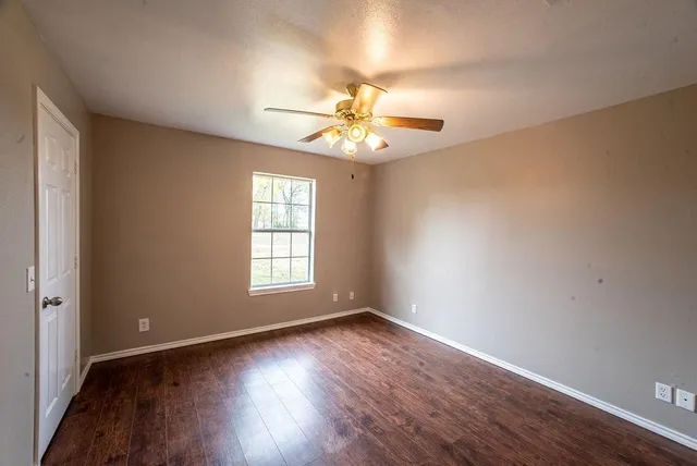 a view of an empty room with window and wooden floor