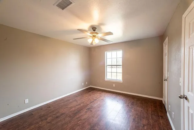 an empty room with wooden floor and window
