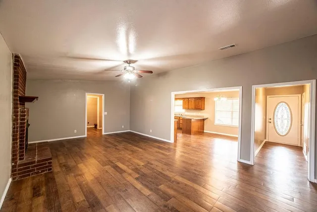 a view of an empty room with window and wooden floor