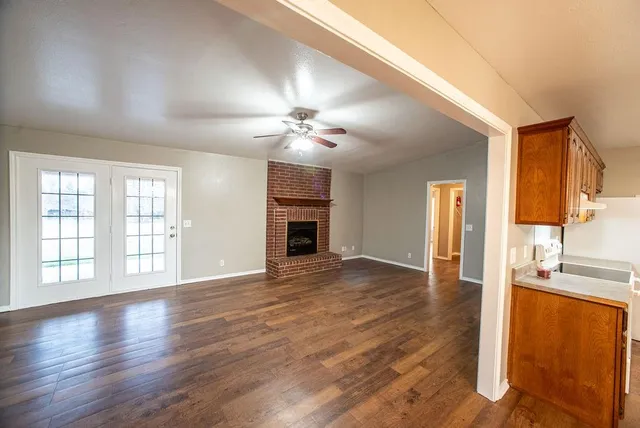 a view of an empty room with window and wooden floor