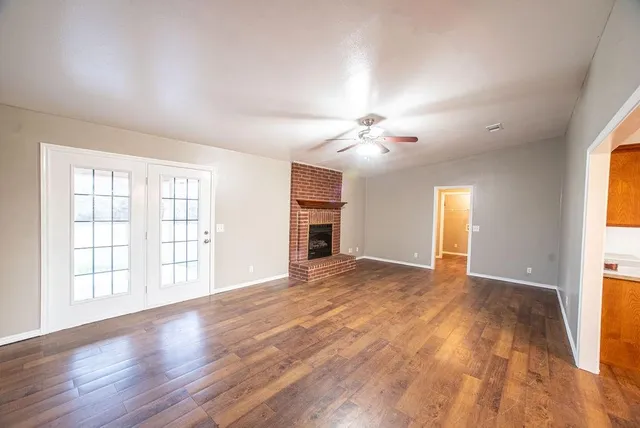 a view of an empty room with a window and wooden floor