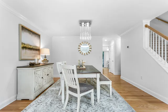 a dining room with wooden floor a chandelier a wooden table and chairs